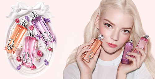 Three Dior fragrance bottles and a Dior lipstick on a colourful, stripy background